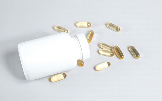 Omega-3 Supplements and Intermittent Fasting - Do They Break Your Fast? A woman taking an omega-3 fish oil supplement pill while intermittent fasting, highlighting the balance between nutrient needs and fasting goals