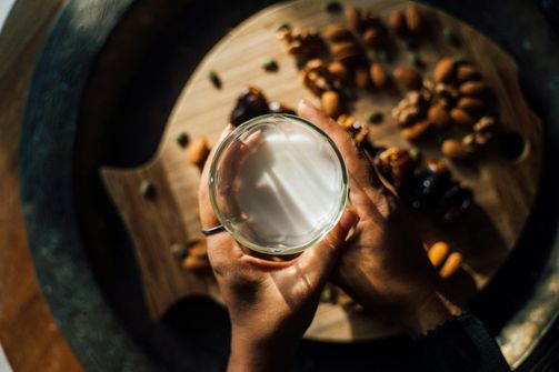 The 2024 Guide to Plant-Based Milks: Nutritional Benefits of Almond, Oat, and Soy for Women’s Health A woman pouring almond milk into a glass, choosing a plant-based option for hydration and wellness.