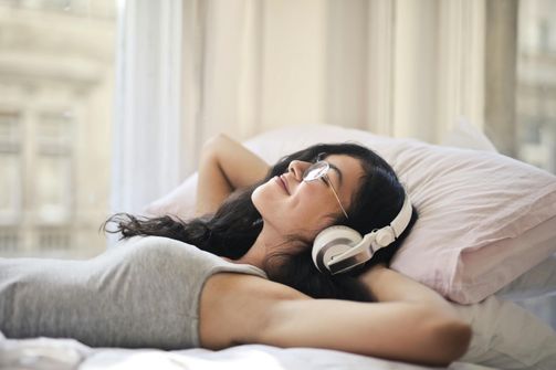 The 2024 Guide to Sound Healing: Sleep Better and Relieve Stress with Binaural Beats and Nature Sounds A woman relaxing before bed, listening to soothing sounds to enhance sleep quality and reduce stress.