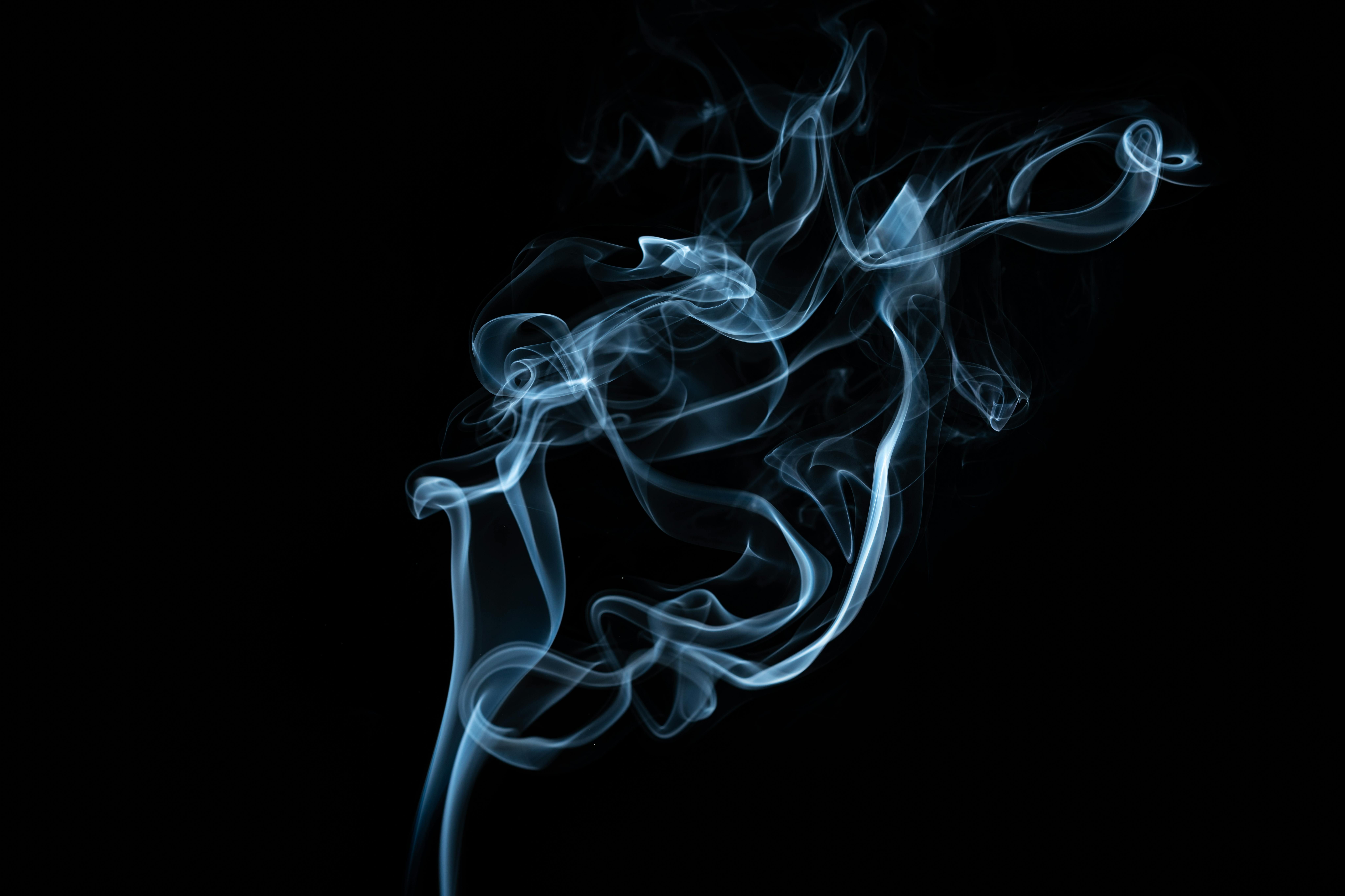 Vape Smoke on Black Background: Visualizing the Hidden Dangers of Vaping Thick vapor cloud from a vape against a black background, highlighting the health risks of vaping.
