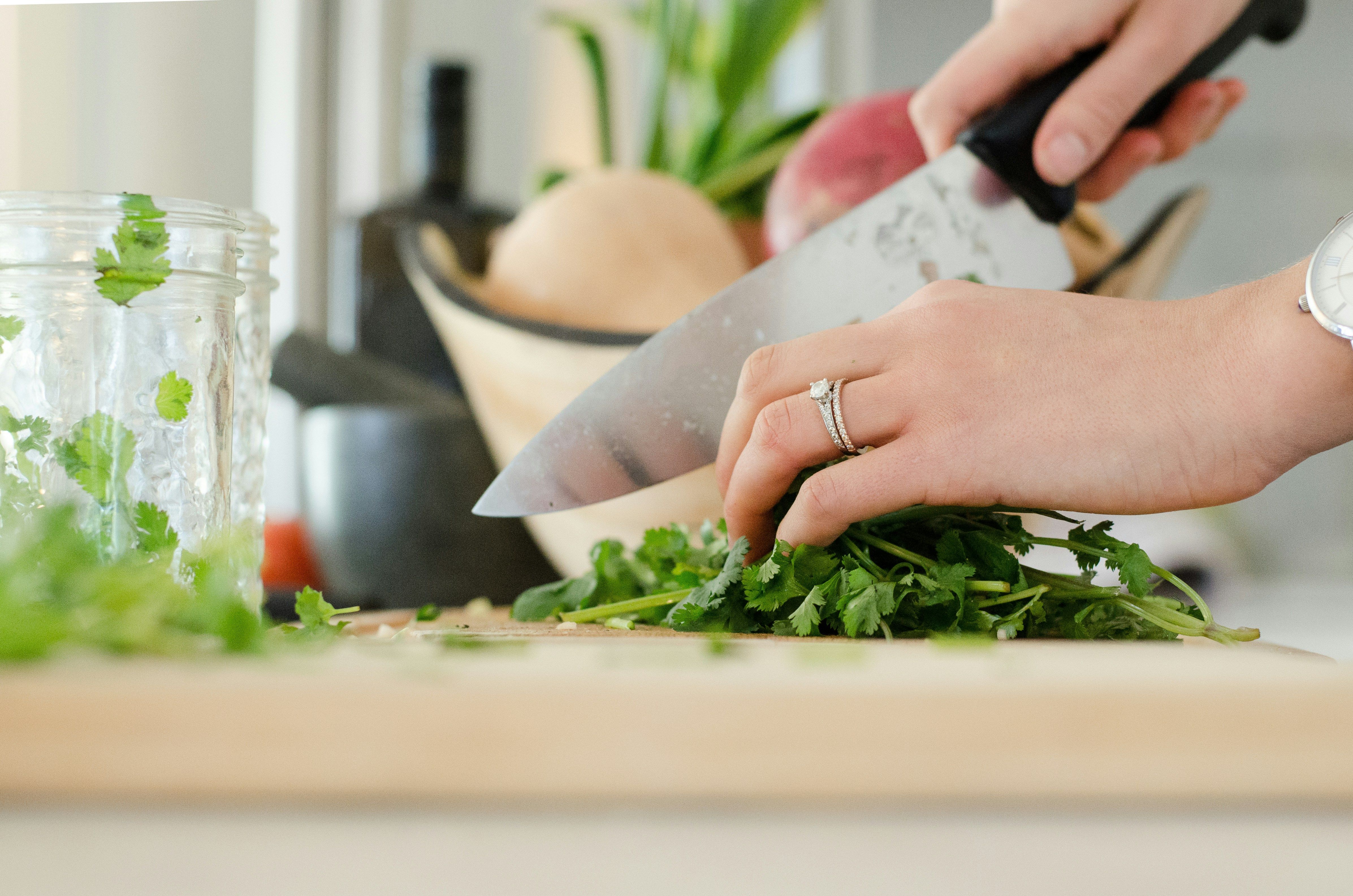 Healthy Cooking at Home: A Woman Prepares Nutritious Meals A woman joyfully preparing healthy meals in her kitchen, chopping fresh vegetables and herbs.
