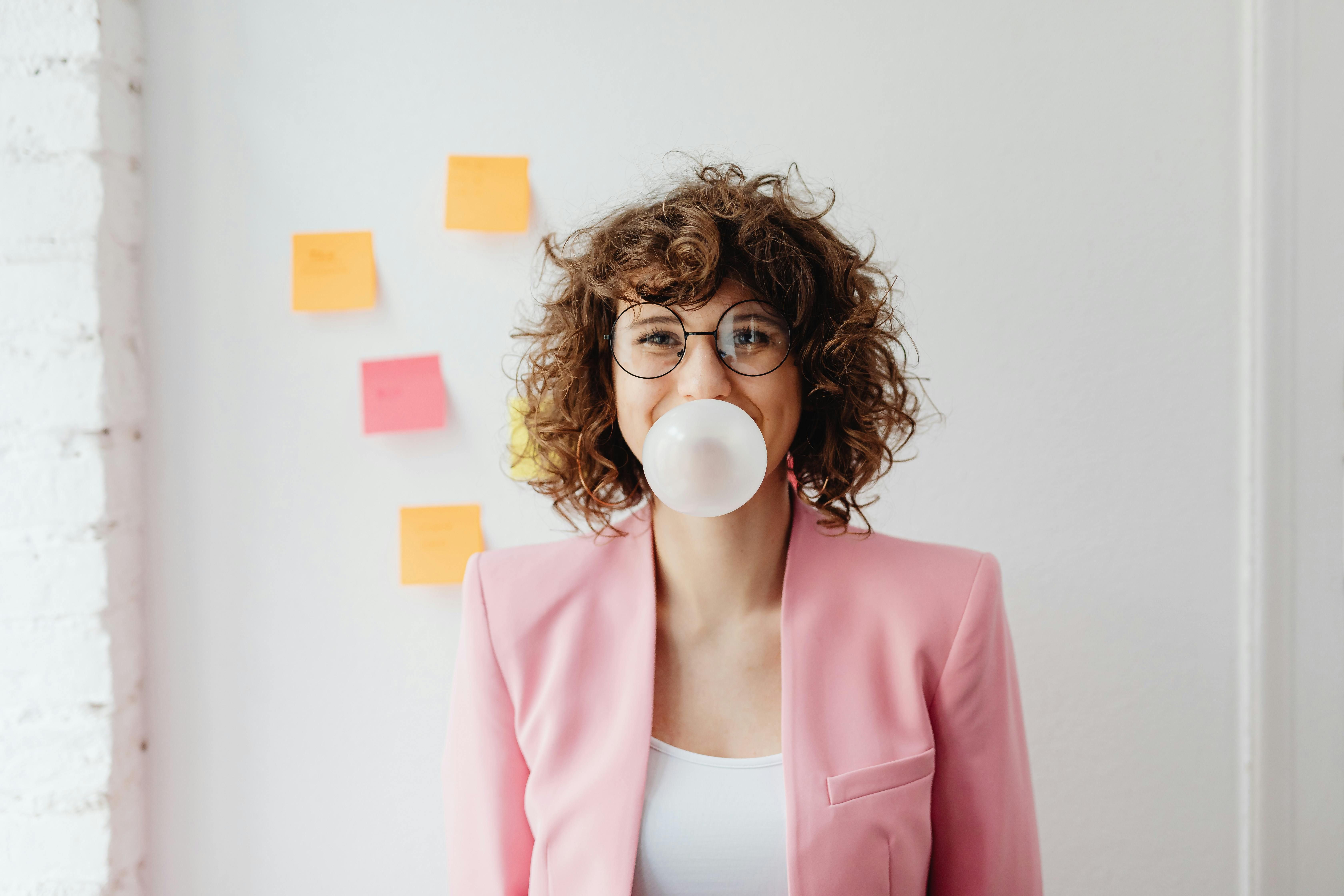Curly-haired woman chewing gum thoughtfully while considering its impact on her fasting regimen