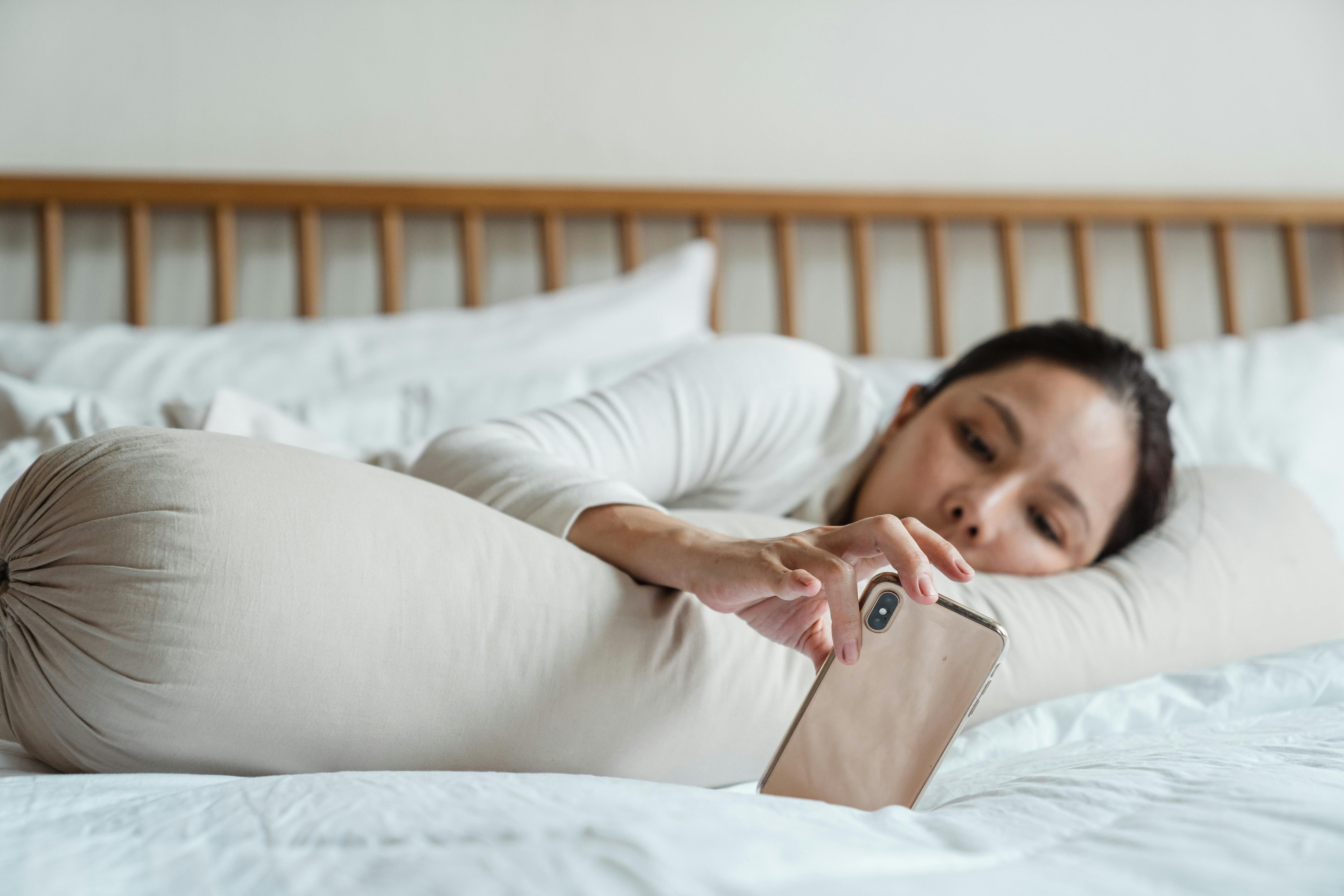 Woman Turning Off Smartphone to Create a Relaxing, Tech-Free Sleep Environment A woman turning off her smartphone before going to sleep, creating a tech-free environment for better rest.