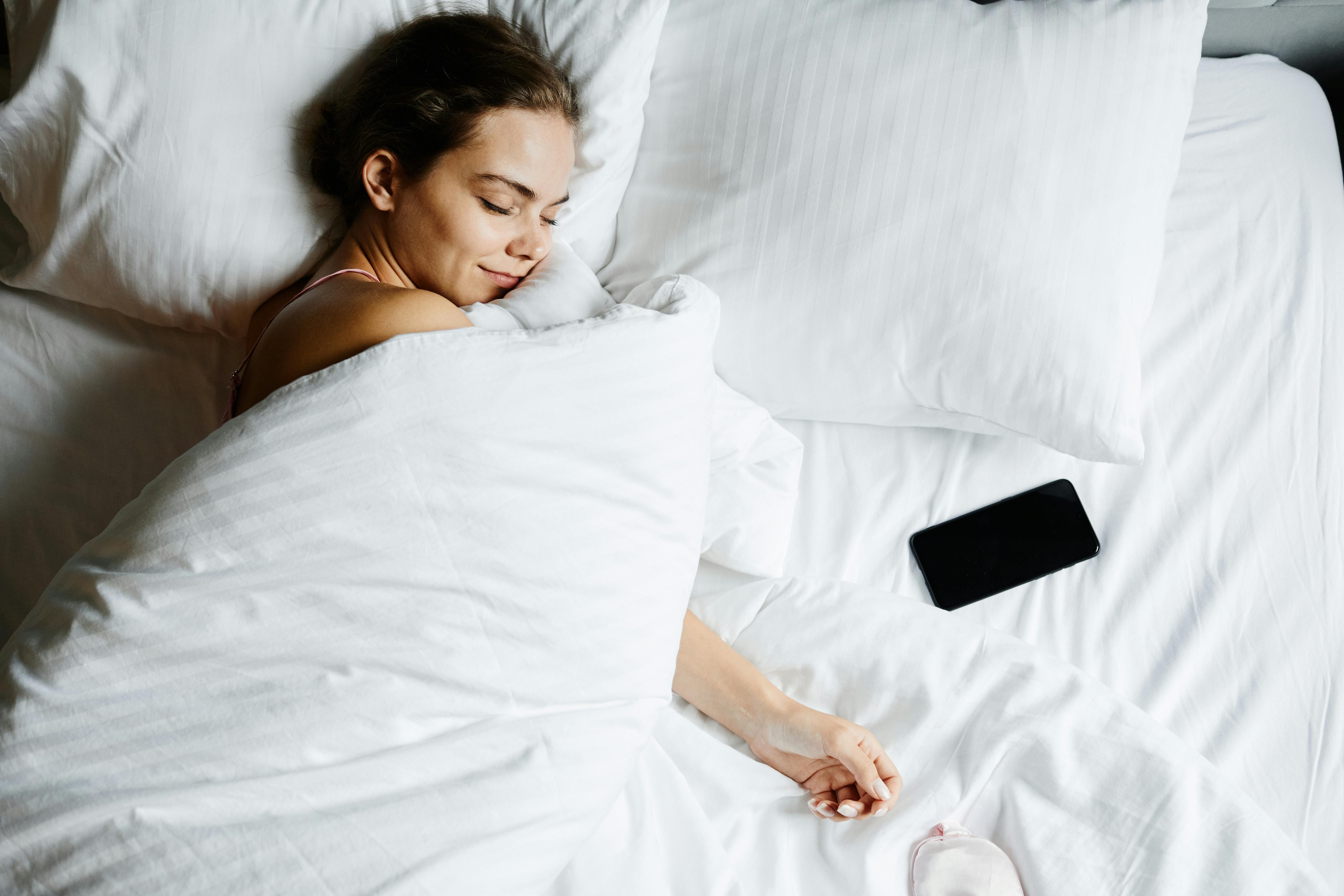 Prioritizing Rest on a Business Trip: Healthy Sleep Habits for Weight Loss A woman sleeping peacefully in a hotel bed, prioritizing rest to support her weight loss goals while on a business trip.